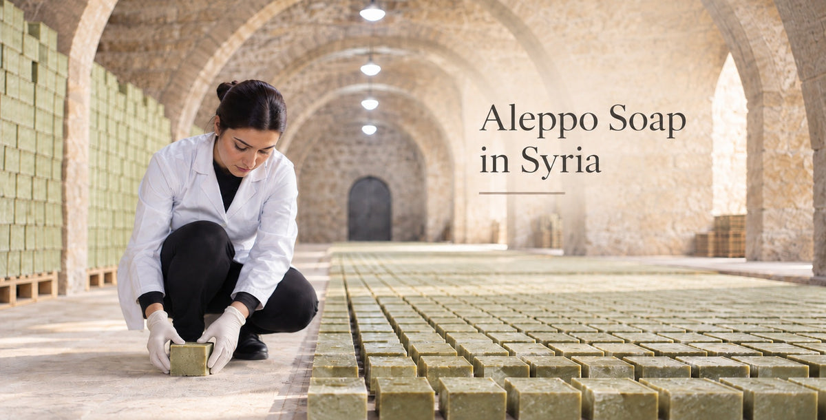 Traditional Aleppo soap drying in a stone workshop in Syria, with stacked olive-and-laurel soap bars and a soapmaker at work.