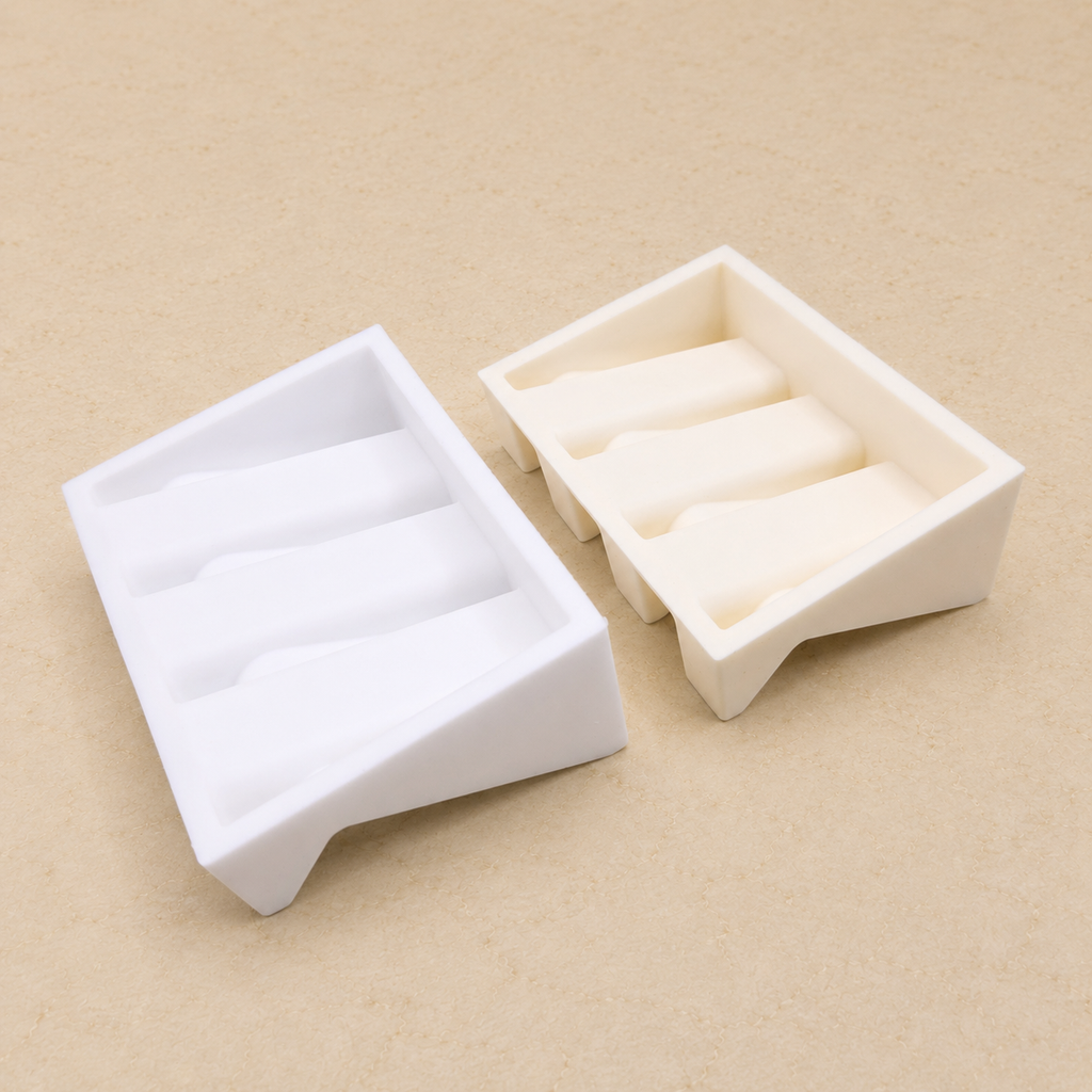 Two soap dishes shown from above on a beige stone countertop, displaying the interior ridges and raised base design.