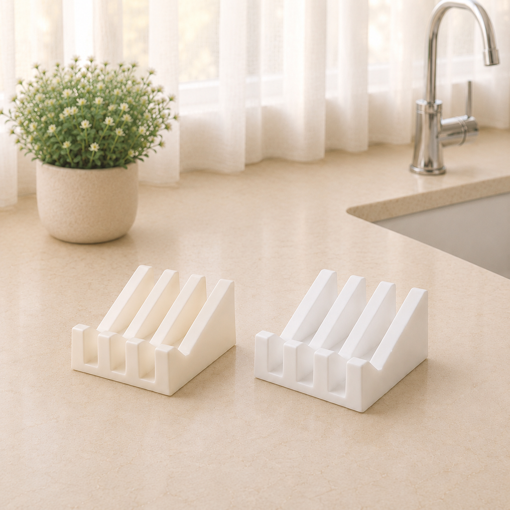 White and ivory ridged soap dishes displayed side by side on a beige bathroom countertop with soft morning light, sheer curtains, a faucet, and a potted floral arrangement.