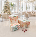 Five Bramble & Bear Cranberry Prosecco Spritz soap bars with coral, yellow, and green marbling are arranged beside three cranberries on a pale stone counter in a bright, holiday-lit hotel lounge.