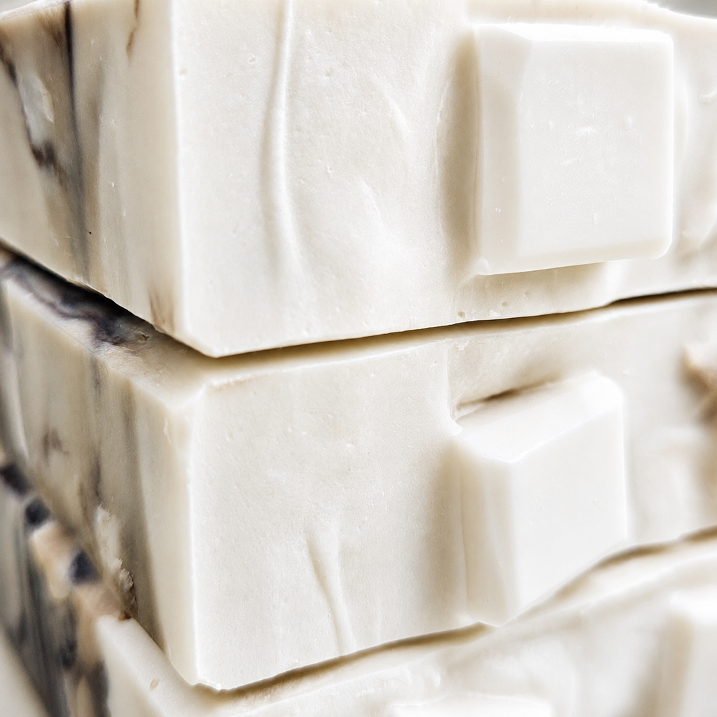 Close-up macro view of Iced Caramel Macchiato soap showing creamy white embeds, smooth beveled edges, and subtle coffee-toned marbling.