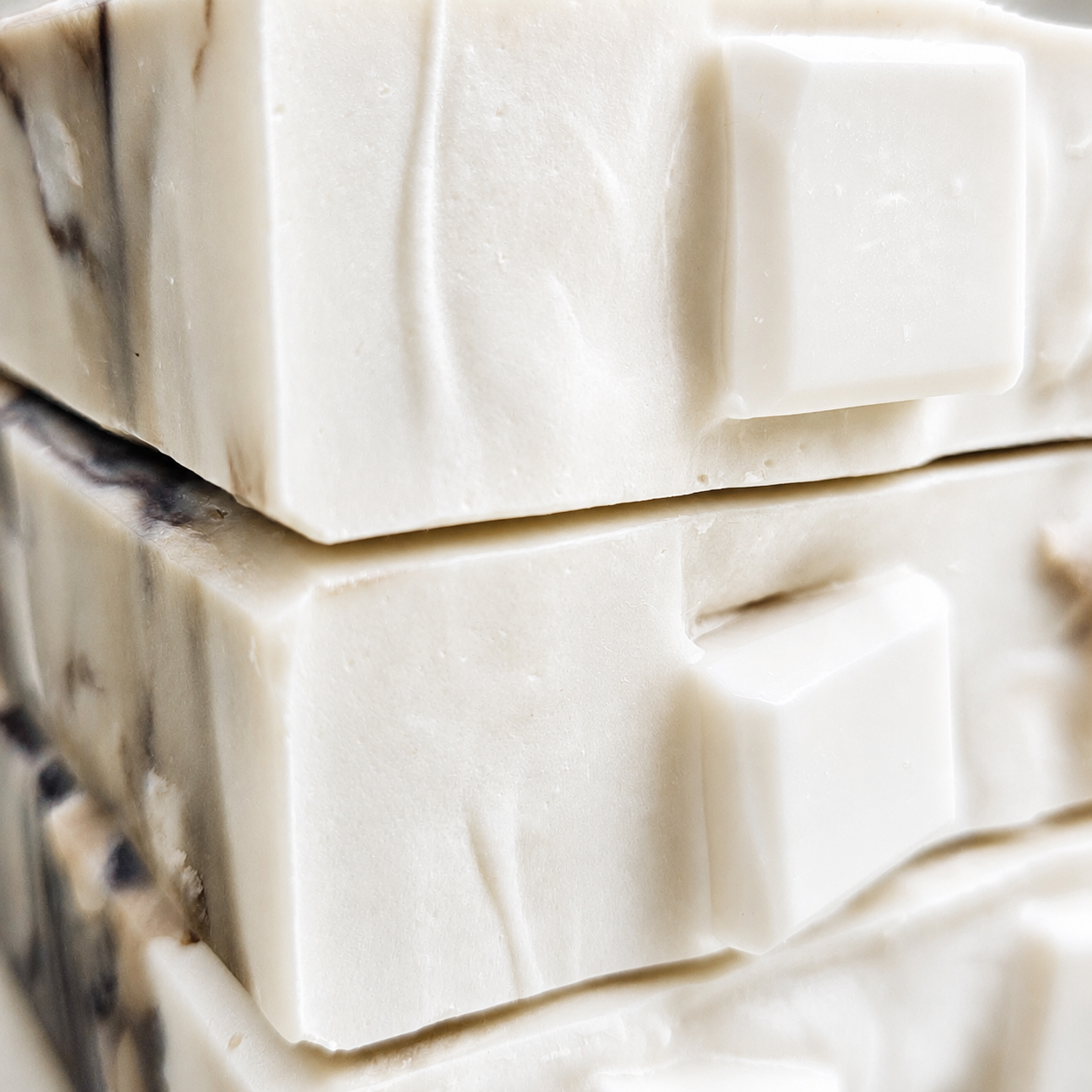 Close-up macro view of Iced Caramel Macchiato soap showing creamy white embeds, smooth beveled edges, and subtle coffee-toned marbling.