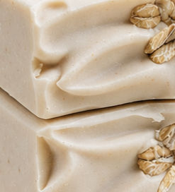 Close-up detail of Honey Oatmeal Grove soap showing creamy swirled texture, fine oatmeal specks, and whole oat grains pressed into the surface.