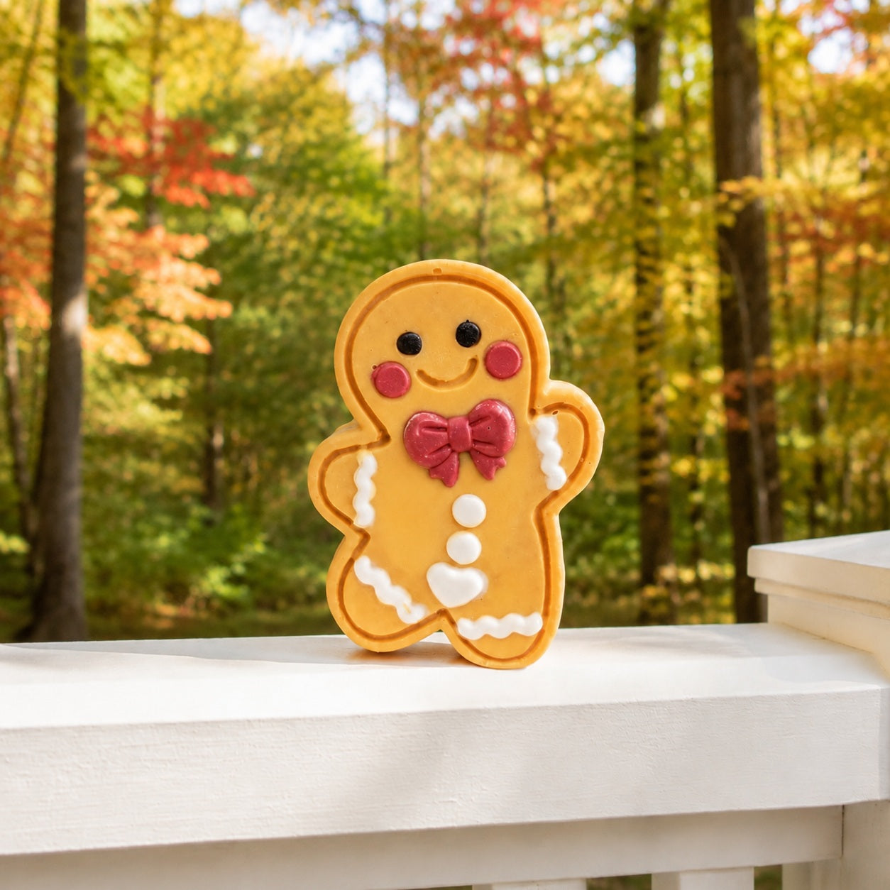 Frosted Pumpkin Apple Cutie soap standing on a white fence rail against a softly blurred autumn woodland.