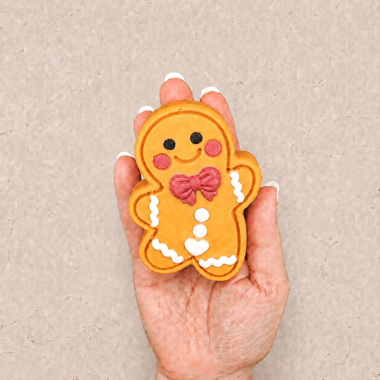 Hand holding a Frosted Pumpkin Apple Cutie soap against a pale stone background to show its size and detailed design.