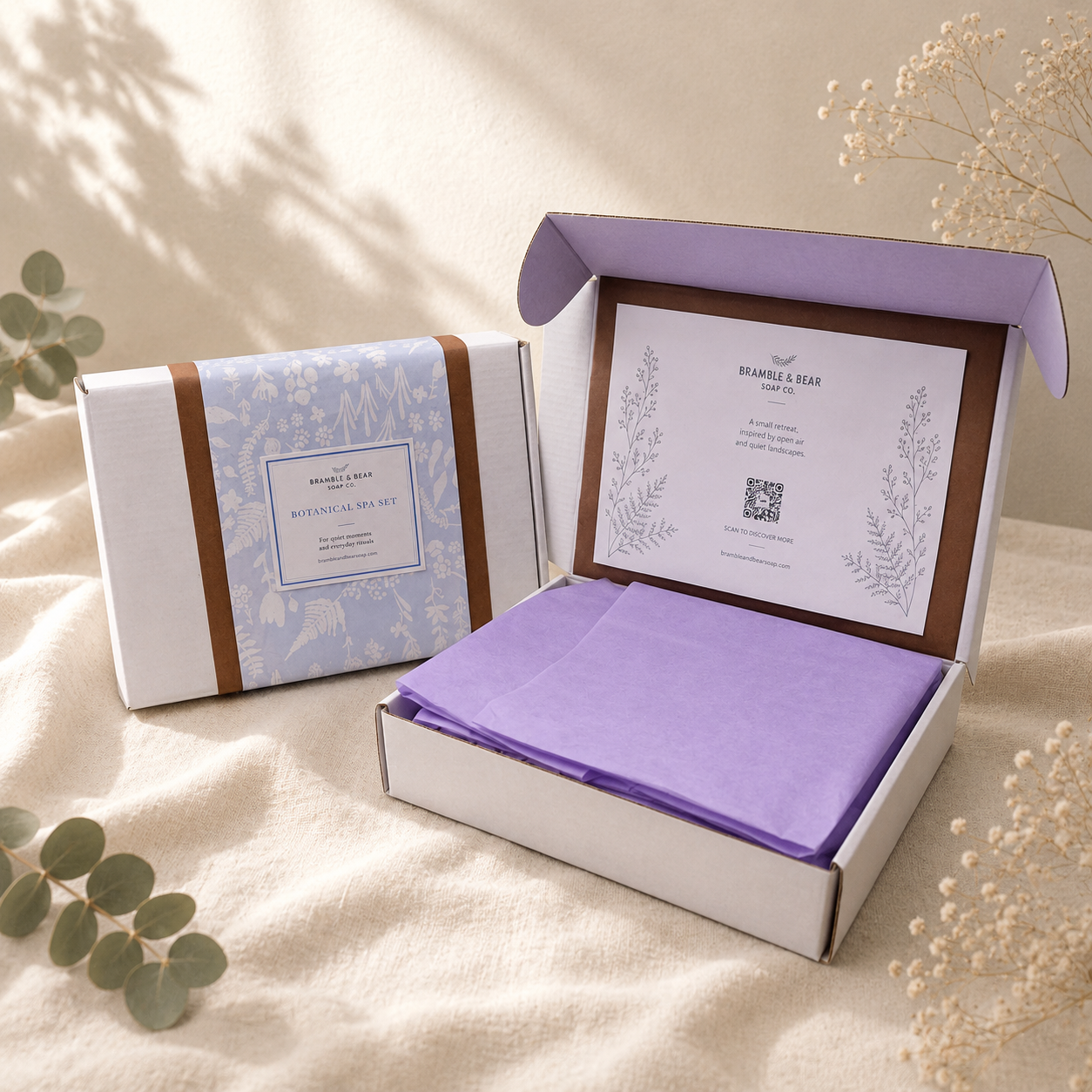 Closed and open Bramble & Bear Signature Collection Ritual Set boxes on ivory linen, showing the interior card and lavender tissue wrapping.