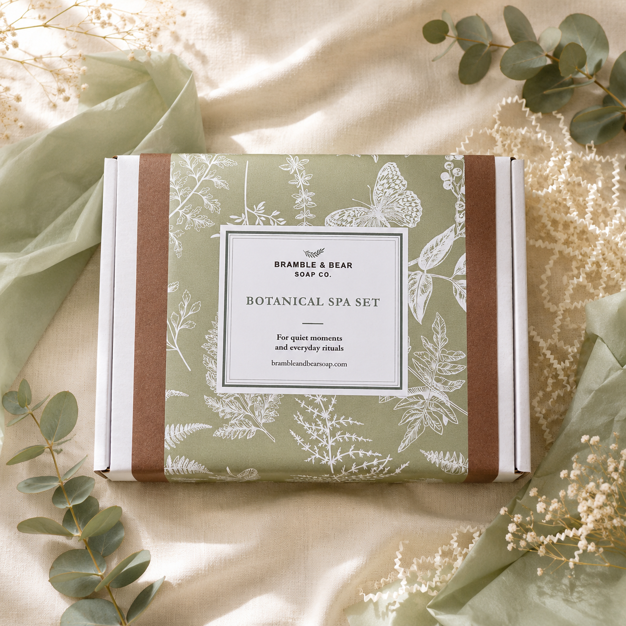 Bramble & Bear Botanical Spa Set gift box in sage botanical wrapping, styled with eucalyptus, tissue paper, and cream crinkle paper.
