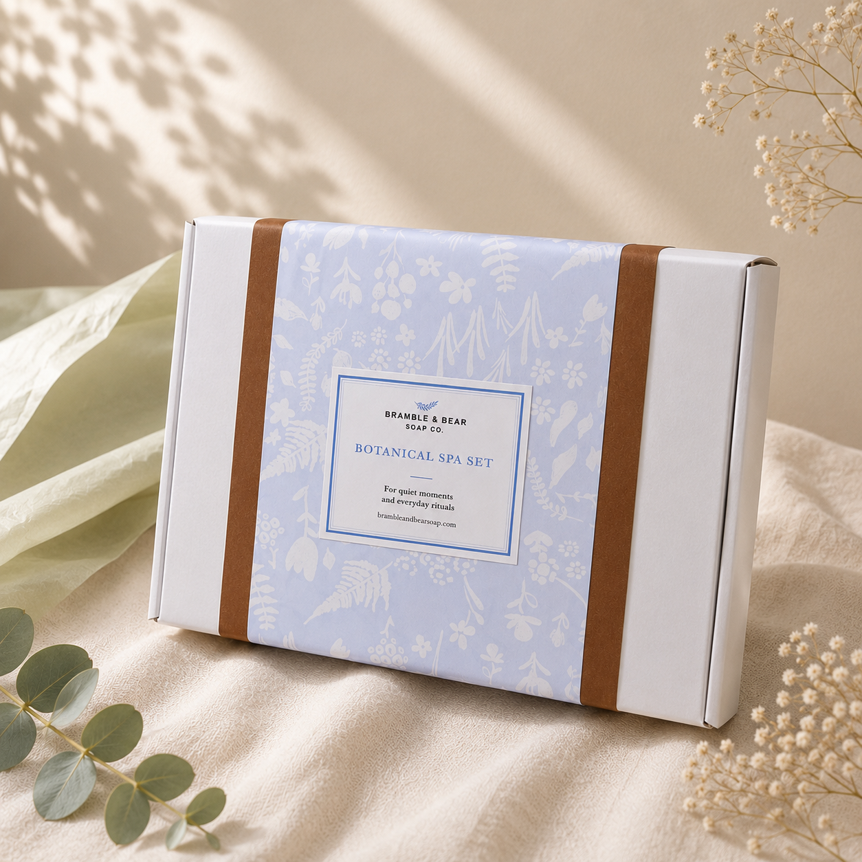 Closed Bramble & Bear Signature Collection Ritual Set in pale blue botanical wrapping, styled on warm ivory linen with eucalyptus and dried botanicals.
