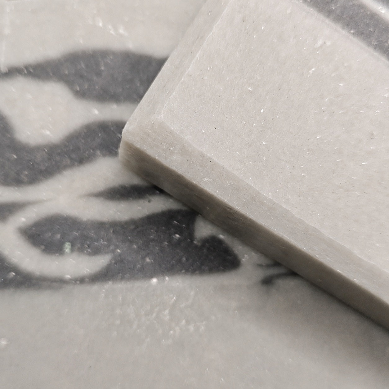Macro view of Silver Birch Crossing soap resting over its birch-inspired charcoal and ivory pattern on pale stone.